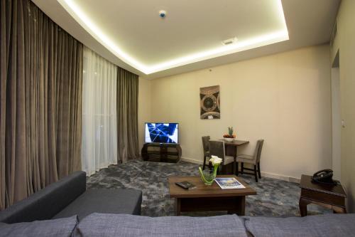 a living room with a couch and a tv at The Town Hotel Doha in Doha