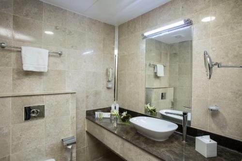 a bathroom with a sink and a mirror at The Town Hotel Doha in Doha