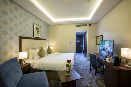 ドーハにあるThe Town Hotel Dohaのベッド、デスク、テレビが備わるホテルルームです。