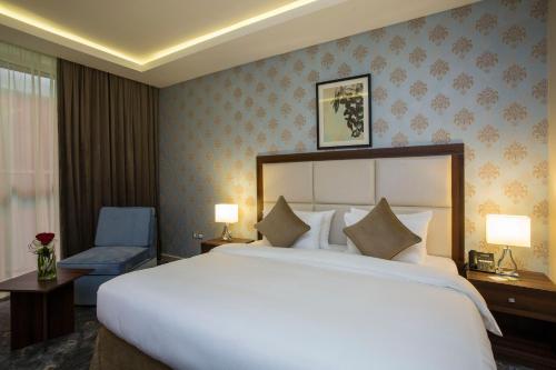 a hotel room with a large bed and a chair at The Town Hotel Doha in Doha