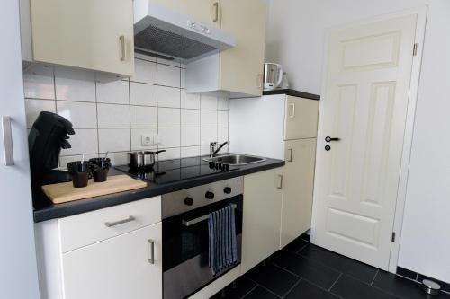 eine kleine Küche mit weißen Schränken und einem Waschbecken in der Unterkunft City Apartment Aurich - Ostfriesland in Aurich