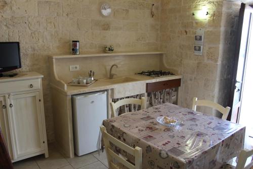 una cucina con tavolo, lavandino, tavolo e sedie di Trullo Monte Grappa ad Alberobello