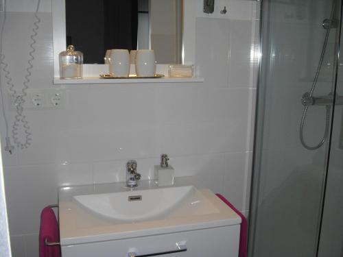 a white bathroom with a sink and a shower at Gästehaus Cramer in Bad Kissingen