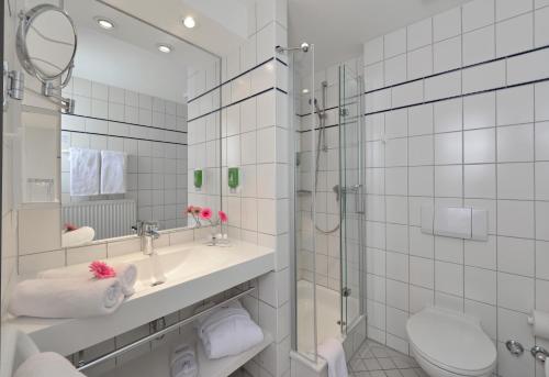 ein Bad mit einem Waschbecken, einer Dusche und einem WC in der Unterkunft Akzent Hotel Haus Surendorff in Bramsche