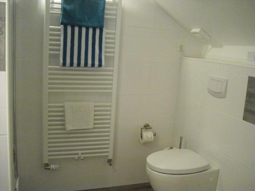 a white bathroom with a toilet and a towel rack at Gästehaus Cramer in Bad Kissingen