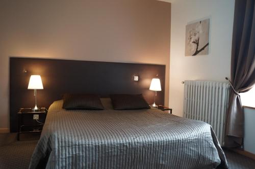 a bedroom with a large bed and two lamps at Hotel du Golf de Clécy in Clécy