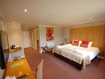 a bedroom with a large bed with red pillows at Kings Court Hotel in Alcester
