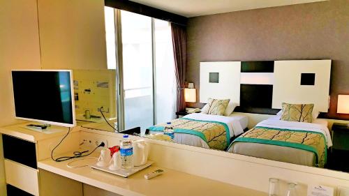 アンタルヤにあるブルー ガーデン ホテルのベッド2台、鏡付きのデスクが備わるホテルルームです。