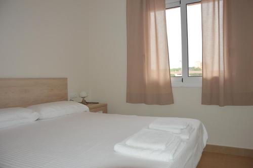 Schlafzimmer mit einem Bett mit weißer Bettwäsche und einem Fenster in der Unterkunft Residencial Super Stop Apartaments Torre Valentina in Sant Antoni de Calonge