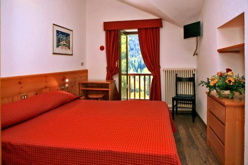 Un dormitorio con una cama roja y un escritorio y una ventana. en Albergo Le Marmotte, en Pré-Saint-Didier