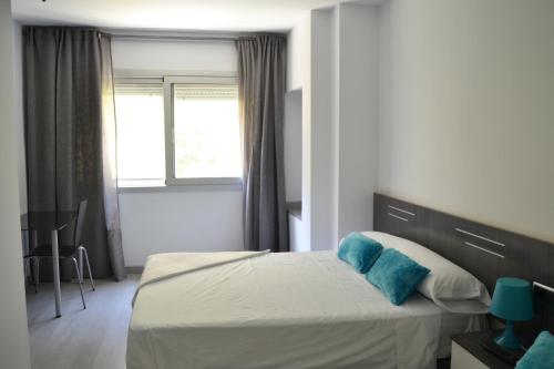 Un dormitorio con una cama con almohadas azules y una ventana en Bed&Breakfast 10 GIRONA, en Girona