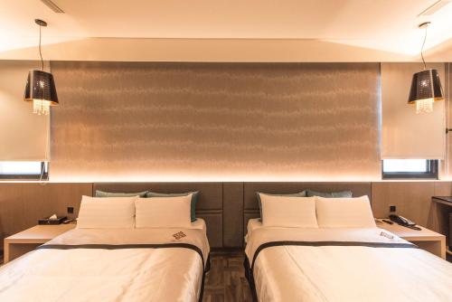 a room with two beds and two tables at Voga Motel in Taichung