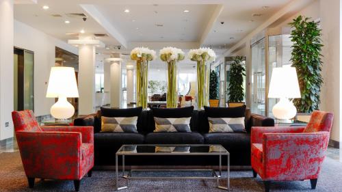 a lobby with a black couch and two red chairs at Herbert Park Hotel and Park Residence in Dublin