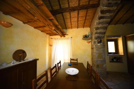 ein Esszimmer mit einem Tisch, Stühlen und einem Fenster in der Unterkunft Lu Rotu in Sant Antonio Di Gallura