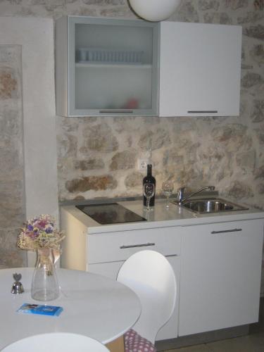 a kitchen with a sink and a table with chairs at Apartment Vidačak in Tisno