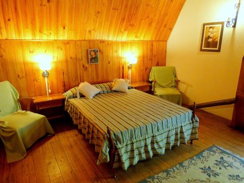 ein Schlafzimmer mit einem Bett und zwei grünen Stühlen in der Unterkunft La Casa del Tata in Potrerillos
