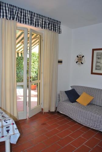 a living room with a couch and a sliding glass door at Bilocali Solaris - Vicini al mare con clima e posti auto in Marina di Campo