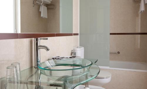 a bathroom with a glass sink and a toilet at Hotel Centro Los Braseros in Burgos