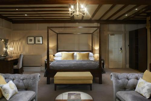 1 Schlafzimmer mit einem Bett, 2 Stühlen und einem Kronleuchter in der Unterkunft The Manor Elstree in Elstree