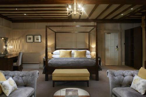 a bedroom with a bed and two chairs and a chandelier at The Manor Elstree in Elstree