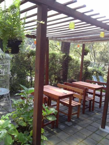 zwei Picknicktische und Bänke unter einer hölzernen Pergola in der Unterkunft Cabañas Monte Alto Hotel Boutique in Valle de Bravo