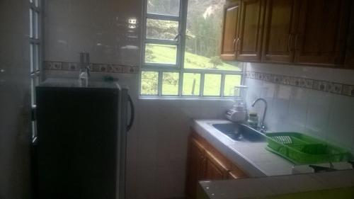 cocina con nevera, fregadero y ventana en Cabaña Los Hayuelos, en Paipa