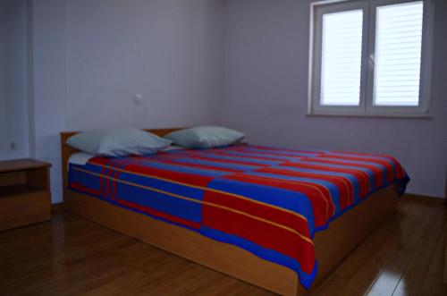 a bedroom with a bed with a colorful blanket on it at Apartmani Mihaela Dobropoljana 52 in Dobropoljana