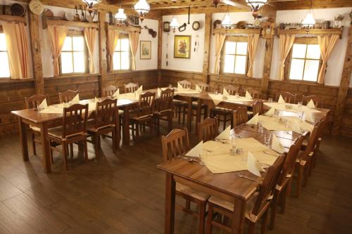 a restaurant with wooden tables and chairs and windows at Relax hotel Valaška in Horní Bečva