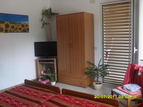 a bedroom with a television and a wooden cabinet at residence la collinetta in Cagli