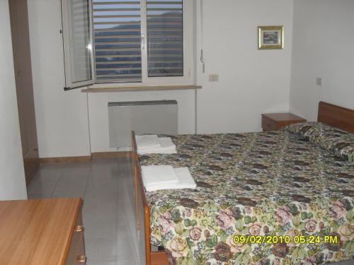 a bedroom with a bed and a desk and a window at residence la collinetta in Cagli