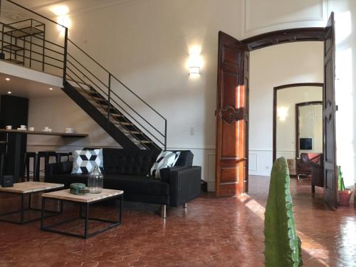 a living room with a black couch and a staircase at Les Suites du Cours & Spa in Aix-en-Provence