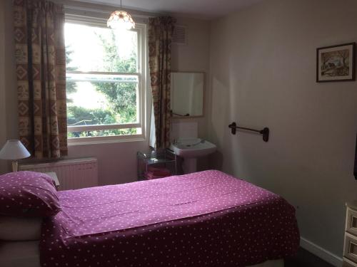 a bedroom with a purple bed and a window at St. James's Guest House in London