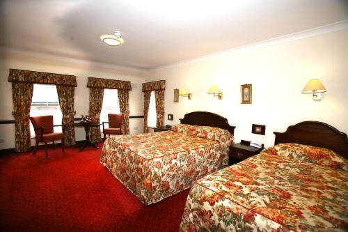 ein Hotelzimmer mit 2 Betten, einem Tisch und Stühlen in der Unterkunft Dorrians Imperial Hotel in Ballyshannon