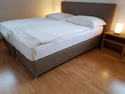 ein großes Bett in einem Schlafzimmer mit einem Nachttisch in der Unterkunft Apartments Krassnig in Krumpendorf am Wörthersee