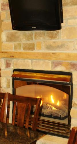 a stone fireplace with a fire in it at Crystal Springs Inn and Suites in Towanda