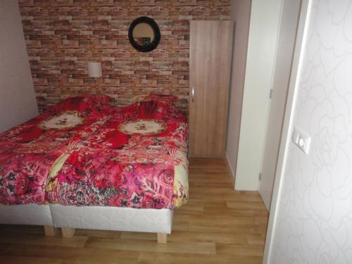 1 dormitorio con cama roja y pared de ladrillo en B&B De Hooiberg en Barneveld