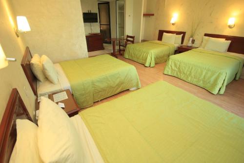 a hotel room with two beds and a couch at Hotel Enterprise Inn Plaza in León