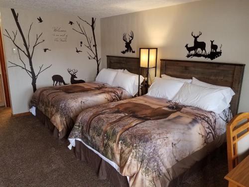 2 camas en un dormitorio con calcomanías de ciervo en la pared en Oakland Motel, en Oakland