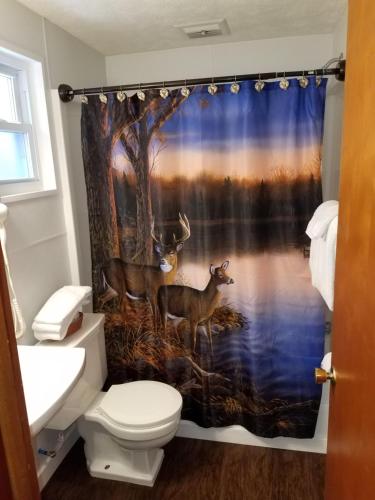 a bathroom with a shower curtain with two deer in the water at Oakland Motel in Oakland