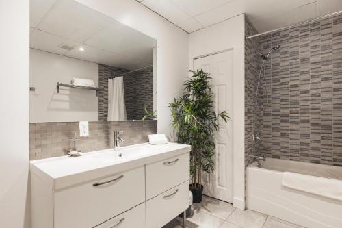 a bathroom with a sink and a tub and a mirror at MtlVacationRentals - The Entertainer in Montreal