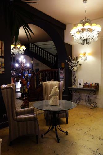 a living room with a table and chairs and a staircase at LOGIS Hôtel de Bourgogne - Mâcon in Mâcon