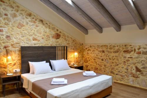 um quarto com uma cama grande e uma parede de pedra em Elia Kentron em Chania Town