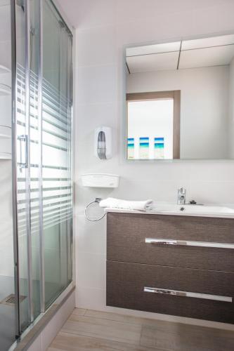 a bathroom with a shower and a sink and a mirror at Hostal Pardo in Miami Platja