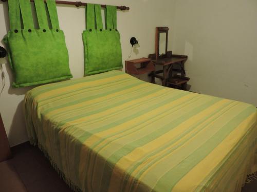 Un dormitorio con una cama con sábanas verdes y una mesa. en Cabañas de la Colina en Villa General Belgrano