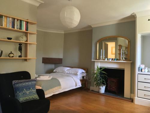 a bedroom with a bed and a mirror and a chair at The Tall House in Totnes