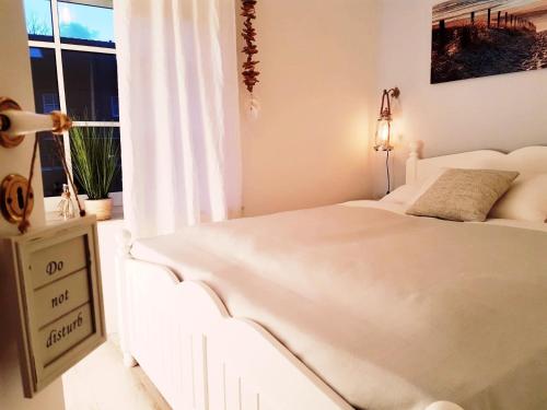 a white bed in a room with a window at Strandgut - das appartement in Schönhagen