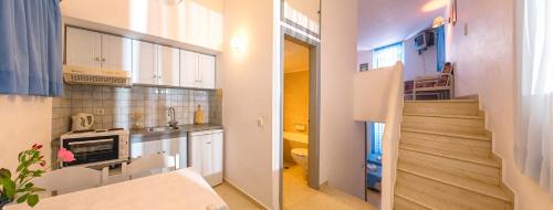 une cuisine avec des placards blancs et un couloir avec un escalier dans l'établissement Primavera Paradise Apartments, à Agios Nikolaos