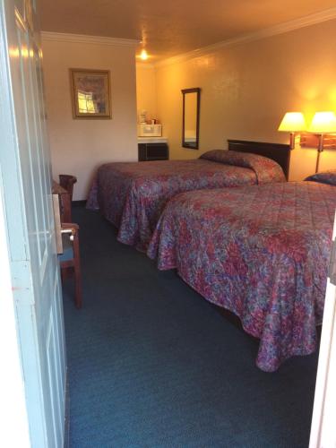 a hotel room with two beds with red sheets at Oak Motel in Palo Alto