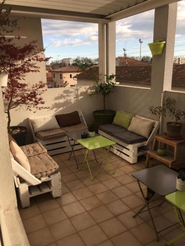 a patio with a couch and a table on a porch at 1 Chambre, 1 P'tit dèj', 1 Sourire in Montpellier