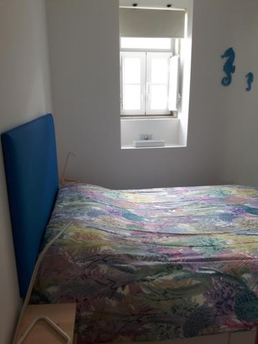 a bedroom with a bed with a colorful blanket on it at Casa do Bairro in Sesimbra